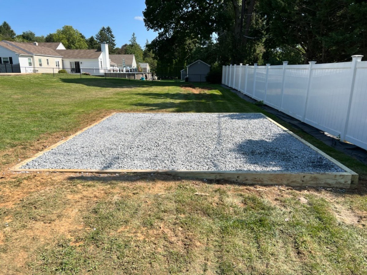 Professional stone pad foundation with treated lumber perimeter and crushed stone